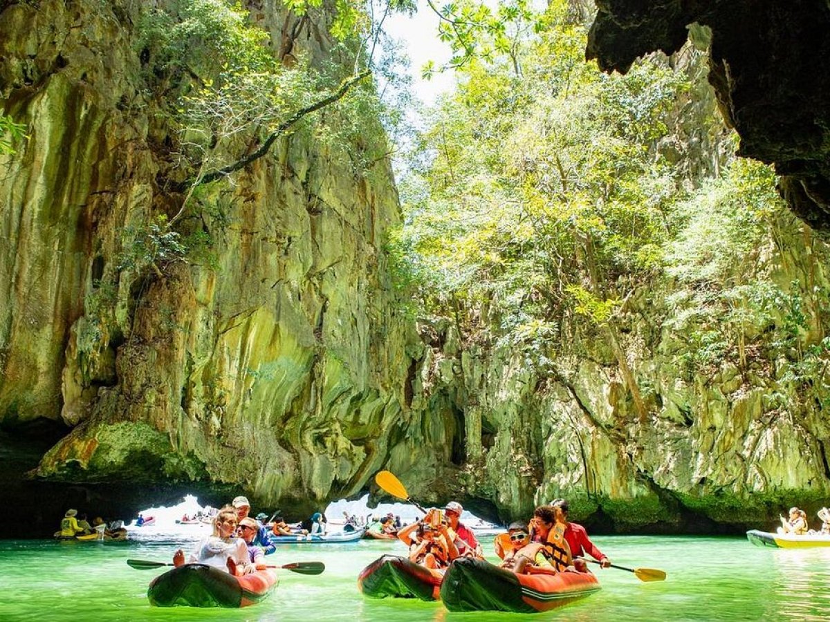 People kayaking through a scenic gorge with lush greenery and rock formations.